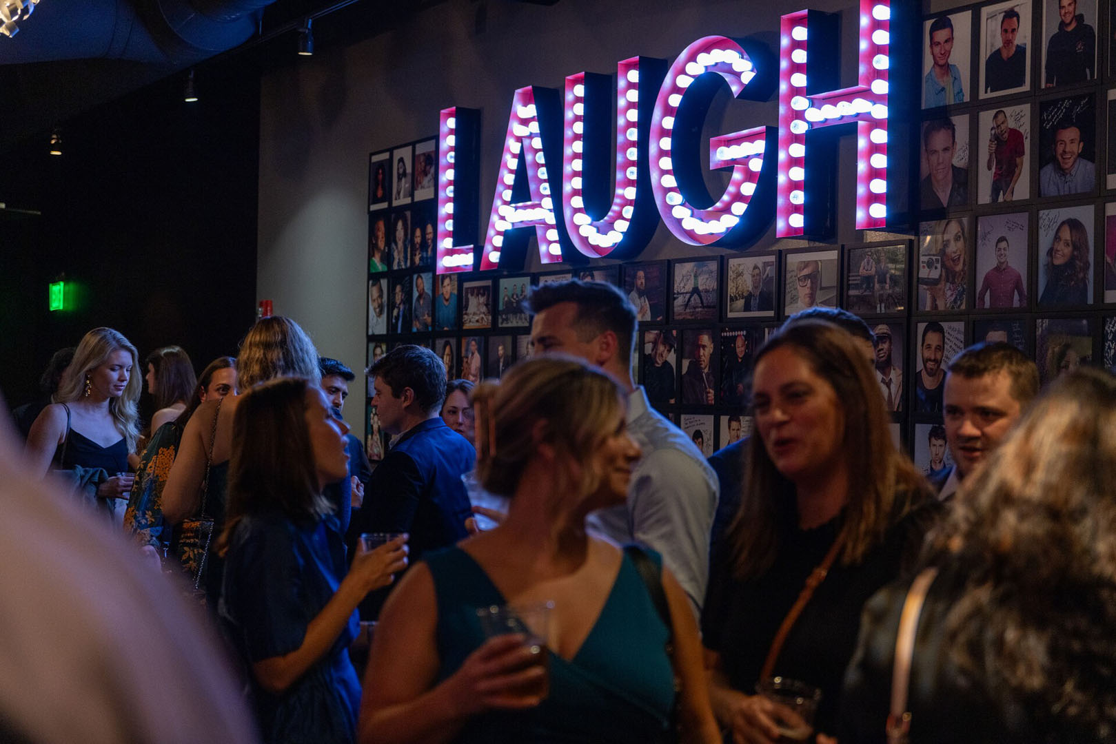 Guests gathering beneath the illuminated LAUGH sign at Laugh Boston