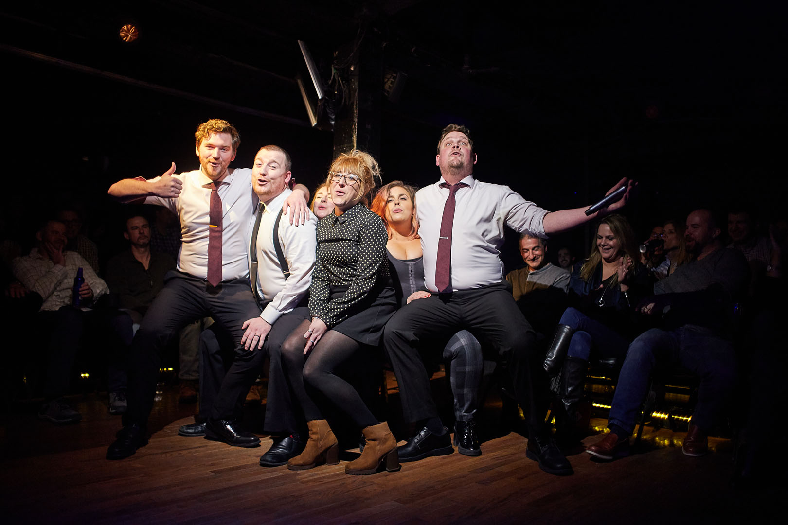 Improv Asylum performers creating a scene together onstage
